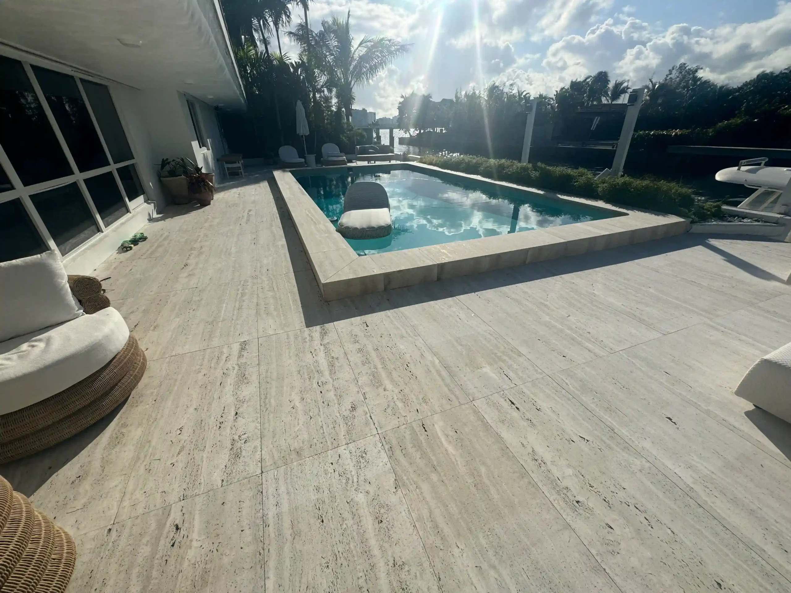 Completed Travertine or Marble paver pool deck installation on a high-end Miami waterfront home. Non-slip, cool-to-the-touch, luxury outdoor living space.