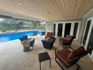 Completed screened pool enclosure and covered patio installation with non-slip French Pattern Travertine pavers in Fort Lauderdale.