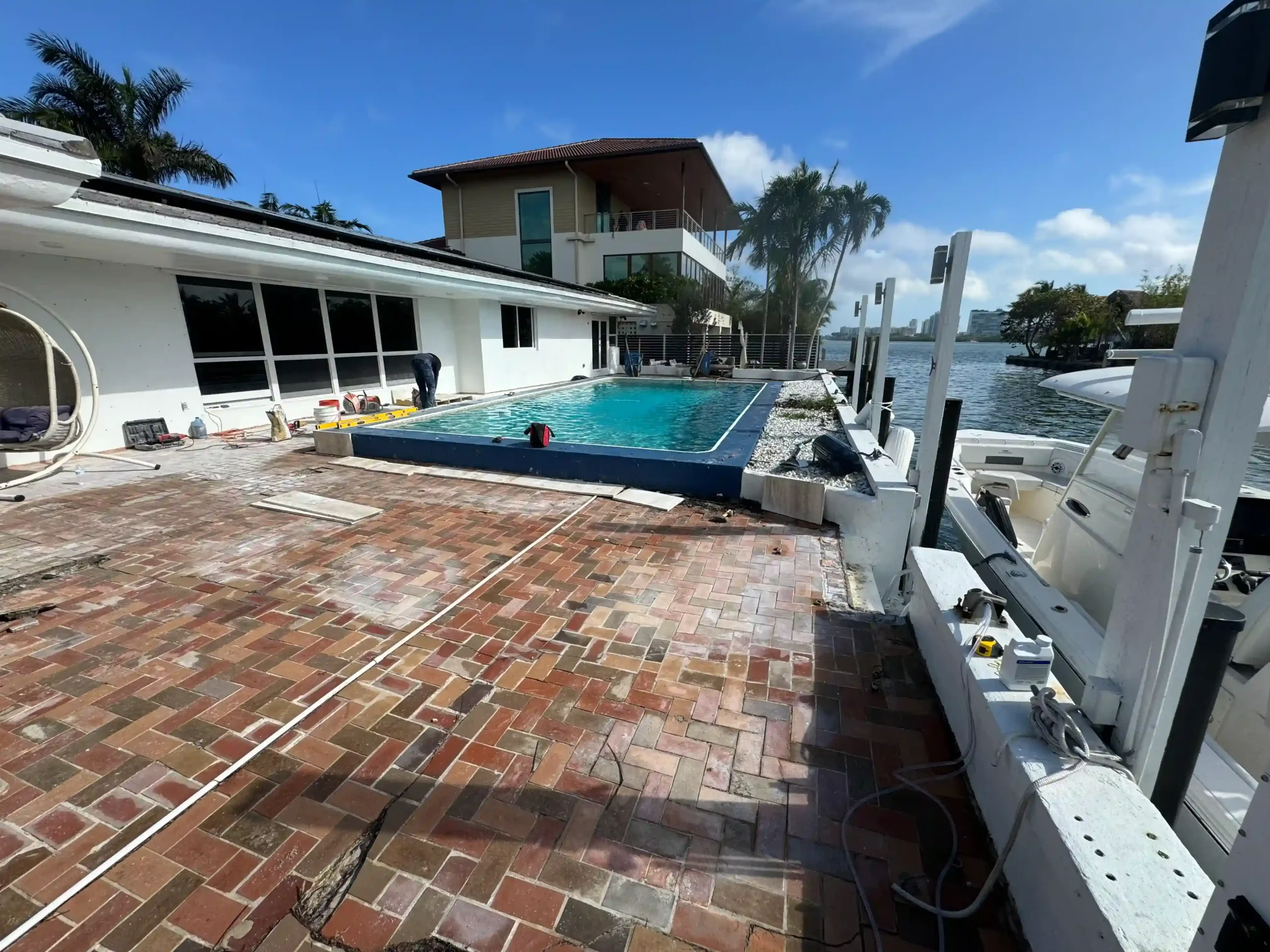 Before photo: Cracked brick pavers on a waterfront pool deck with boat dock in Miami. Needs marine-grade paver replacement.