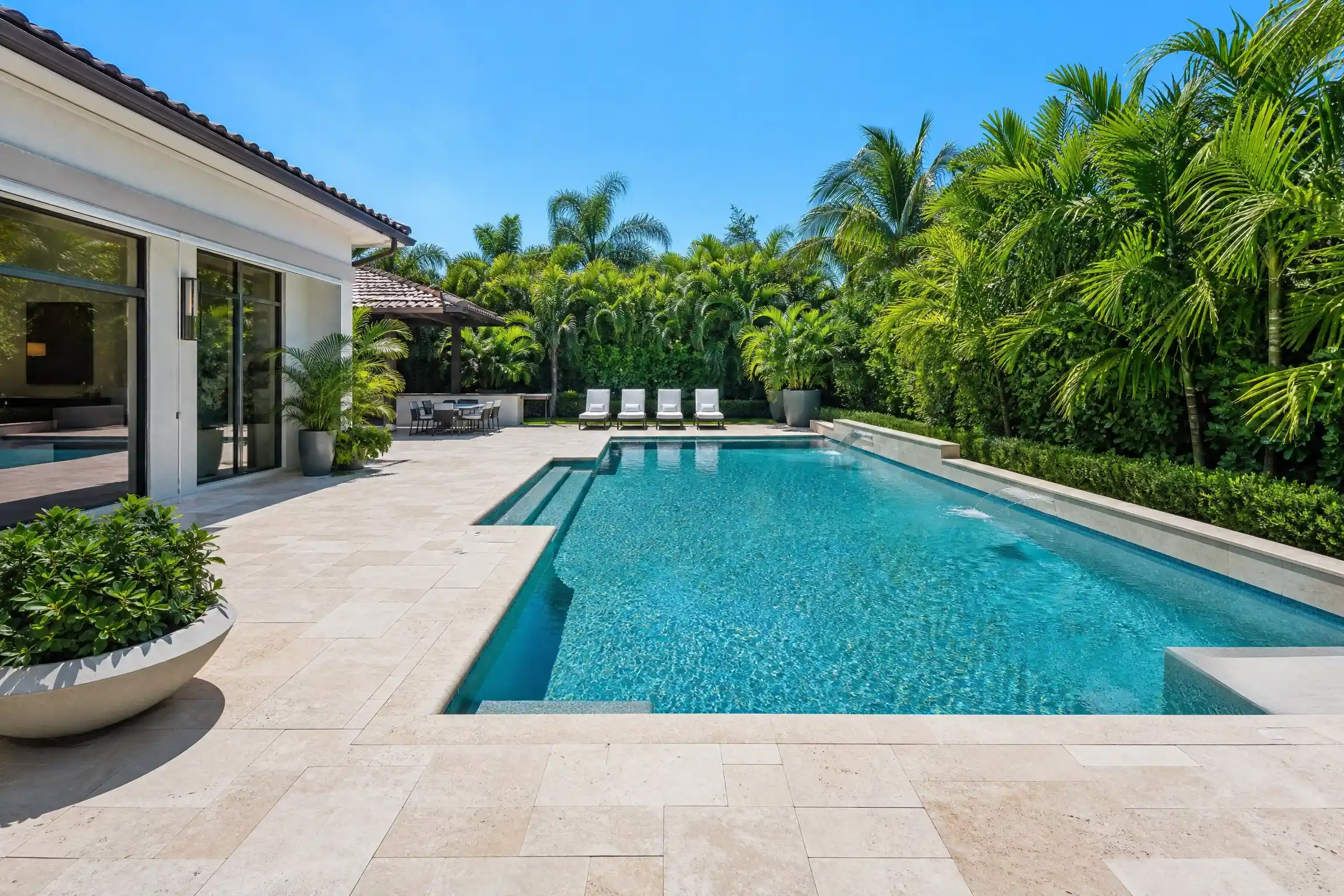 Beautiful backyard pool surrounded by pavers and lush tropical plants.